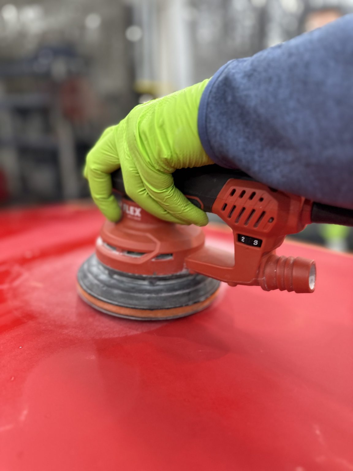 Ponçage d’une carrosserie rouge à la ponceuse orbitale, formation polissage et ponçage auto en Belgique